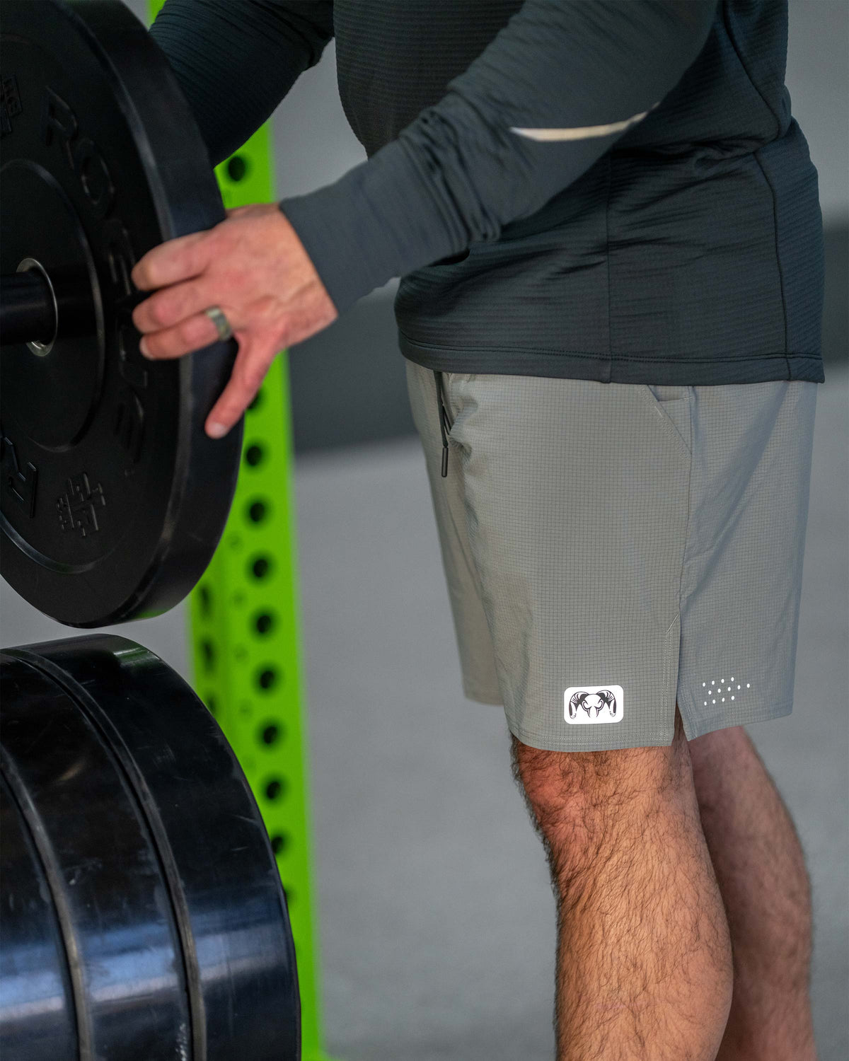 Man adjusting weight plate while wearing EnduroTrainer 7" Short in Shadow Grey