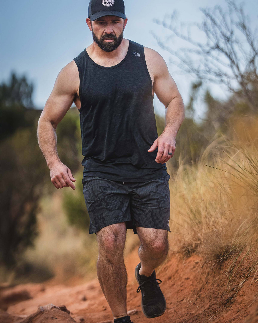Man running on a trail wearing an EnduroMesh Tank in Black.