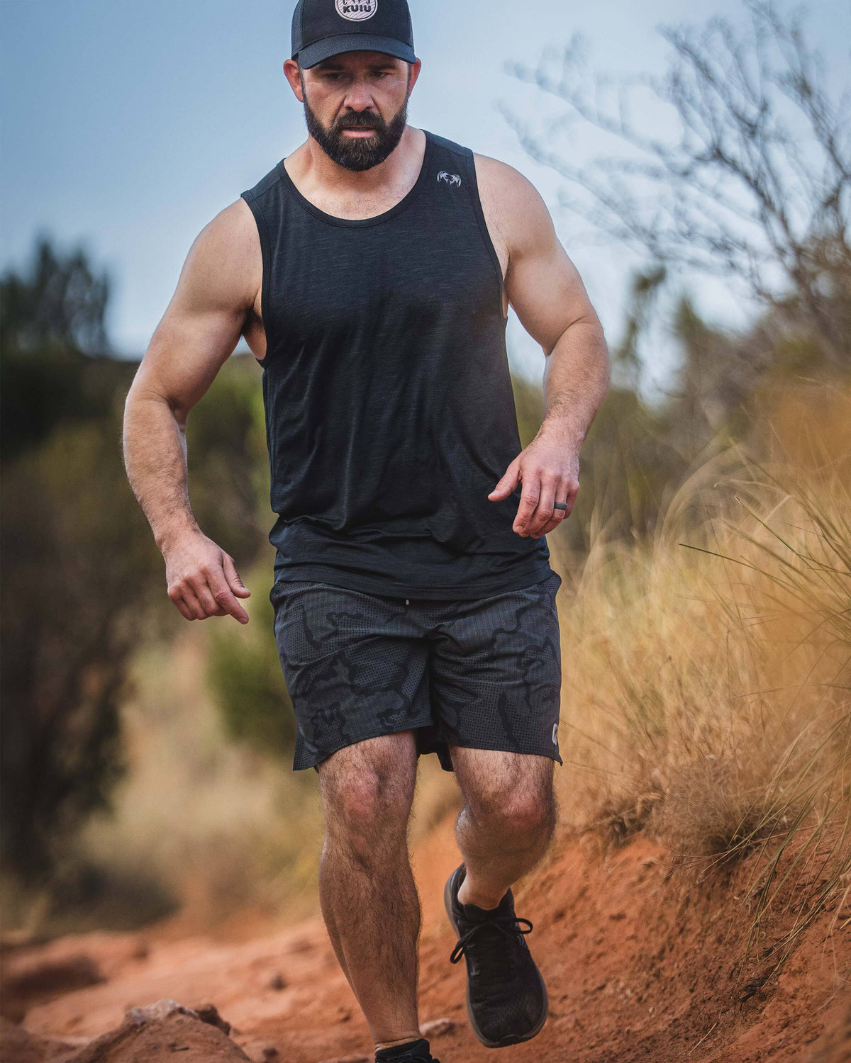 Man running on a trail wearing an EnduroMesh Tank in Black.