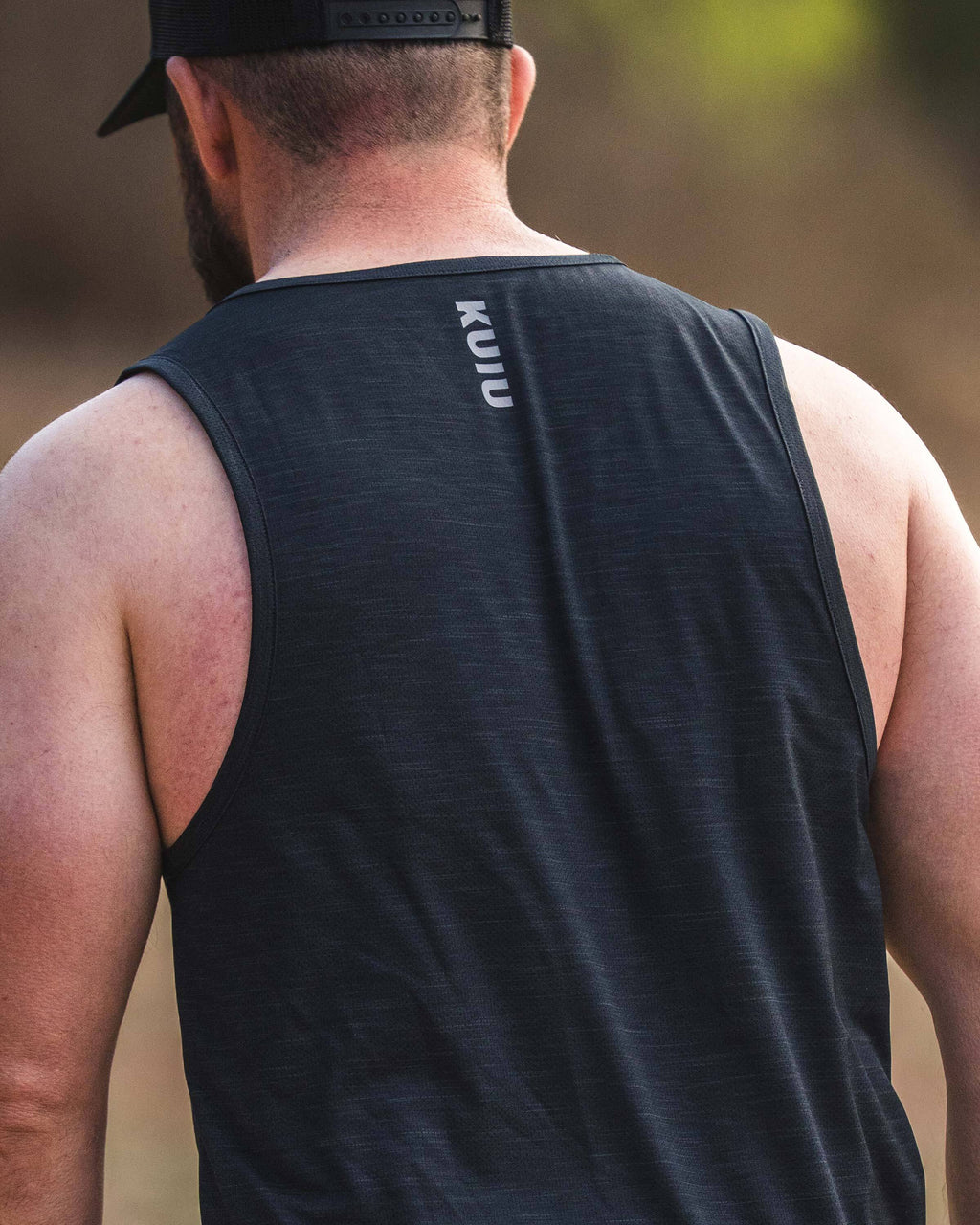 Back view of a man in an outdoor setting, wearing a EnduroMesh Tank in Black.