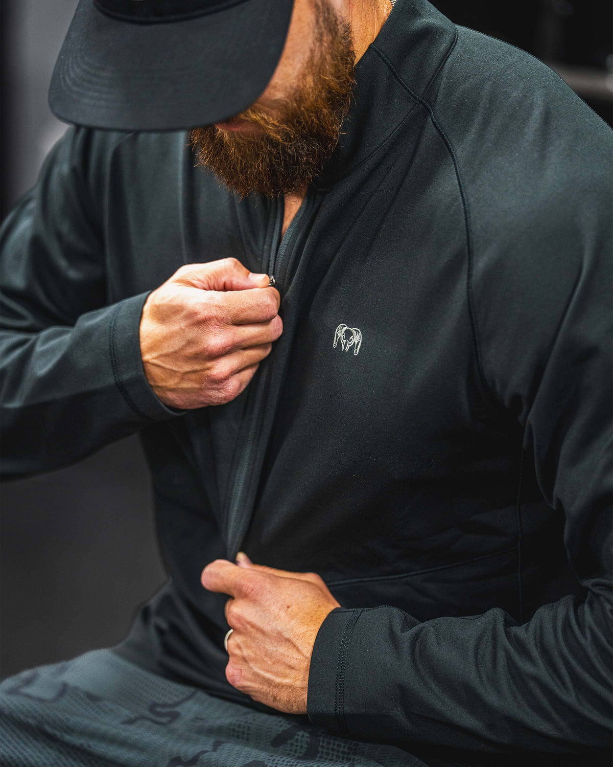 A close-up of a man wearing a TrailTrainer Fleece Zip-T in Black, pulling the zipper tab.
