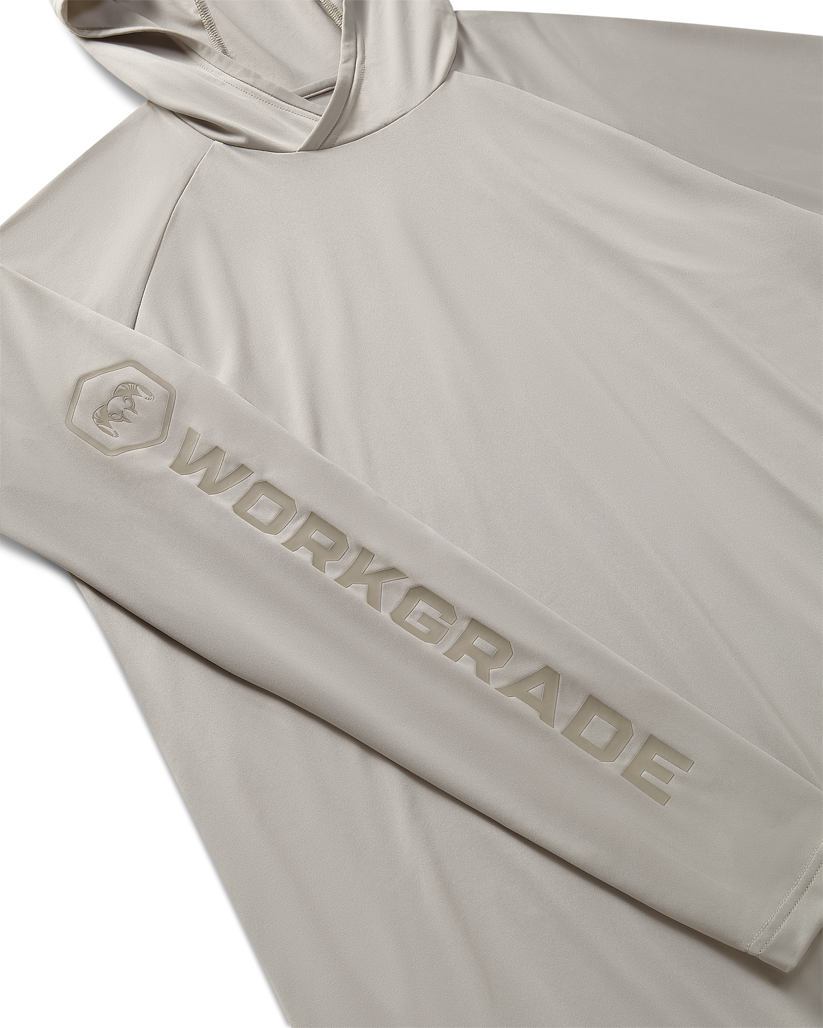 Close-up, flat lay of a Workgrade Long Sleeve Sun Hoodie in Haze Grey laid flat, highlighting the sleeve with a bold “WORKGRADE” logo and hex emblem of a ram printed along the arm.