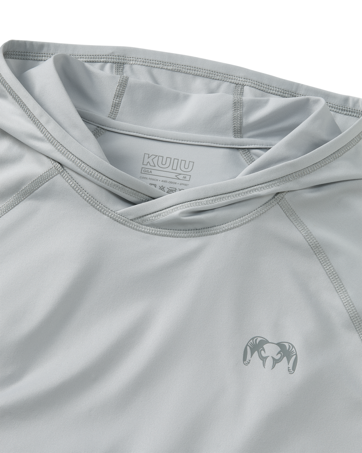 Close-up flat lay view of flatlock seams, folded hood, and KUIU Ram logo on left chest of Gila Long Sleeve Hoodie in Lunar Grey
