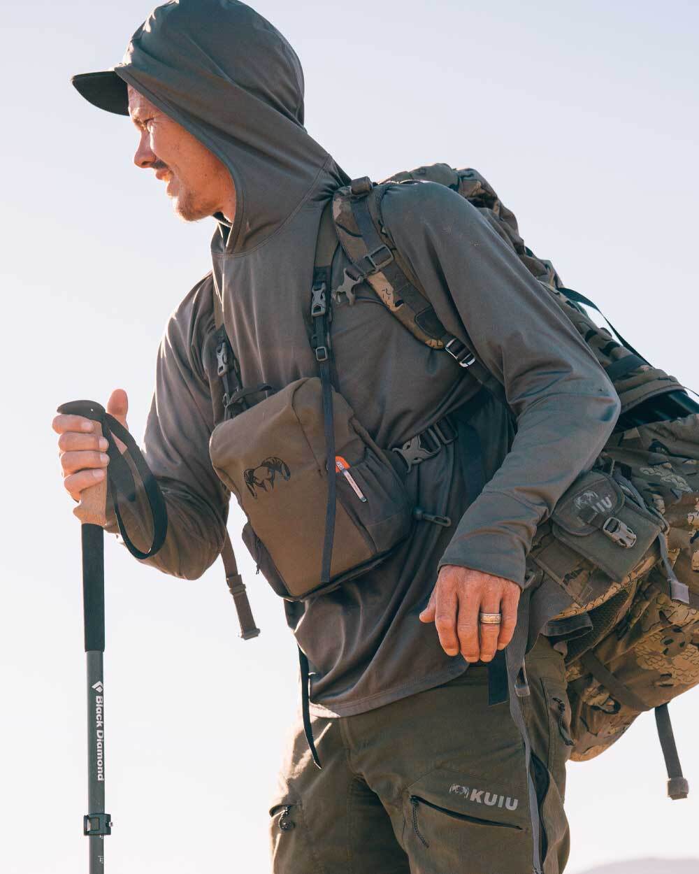 Closeup hunter's side profile view, hiking, wearing Gila Long Sleeve Hoodie in Stone Grey