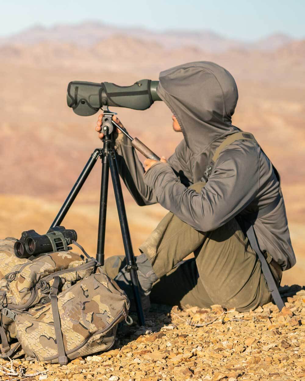 Closeup hunter's side profile view, hiking, wearing Gila Long Sleeve Hoodie in Stone Grey