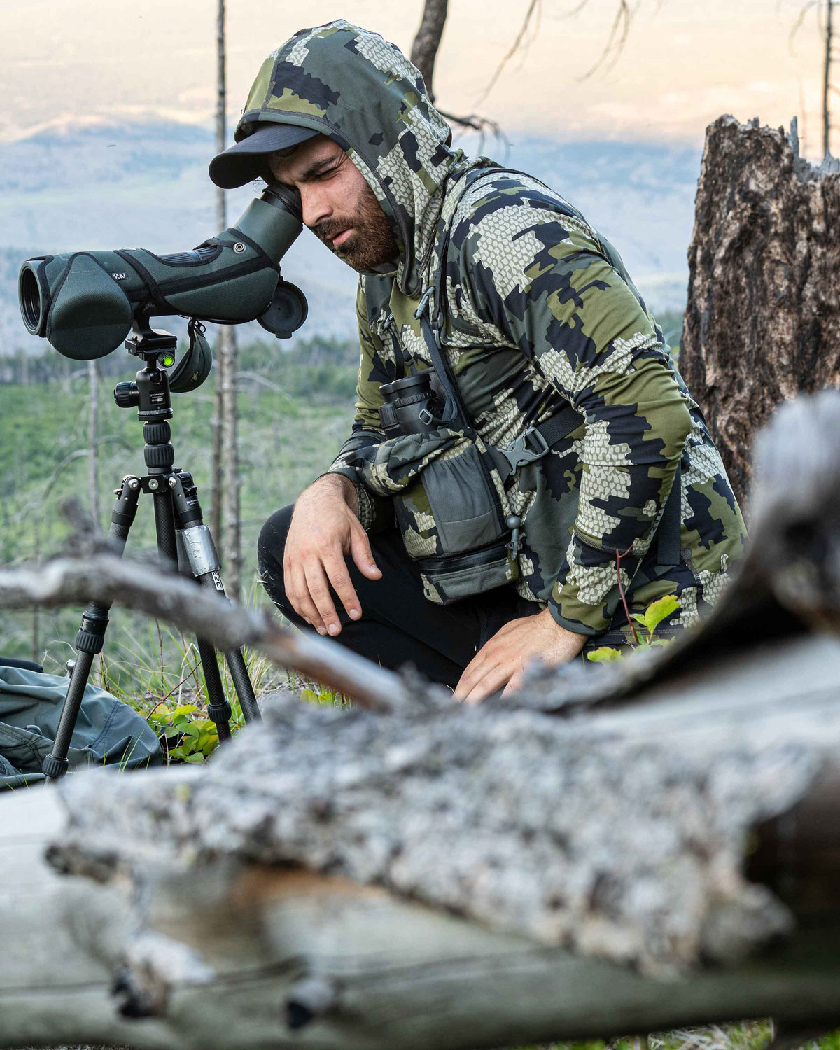Side of Hunter Looking through Spotting Scope in Gila Long Sleeve Hoodie in Verde Camouflage