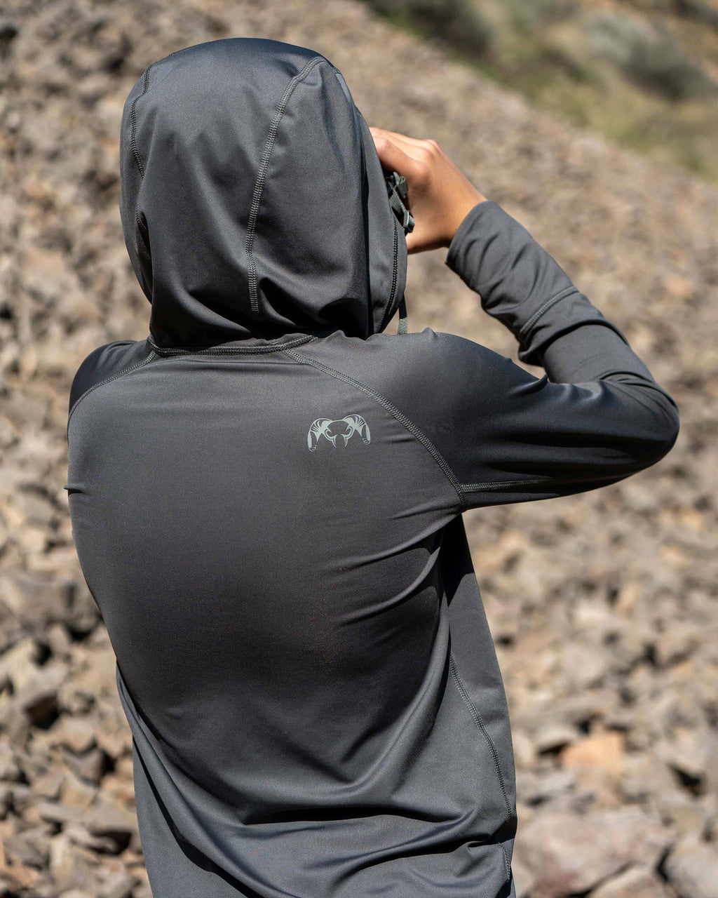 Back side view of Youth glassing, wearing Youth Gila Long Sleeve Hoodie in Stone Grey 