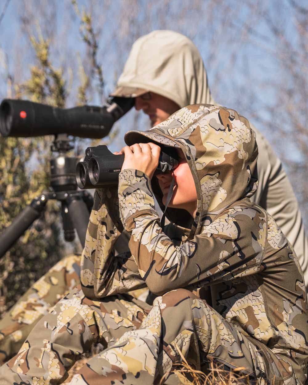 Youth hunter glassing wearing Youth Gila LS Hoodie in Valo Camouflage using hood