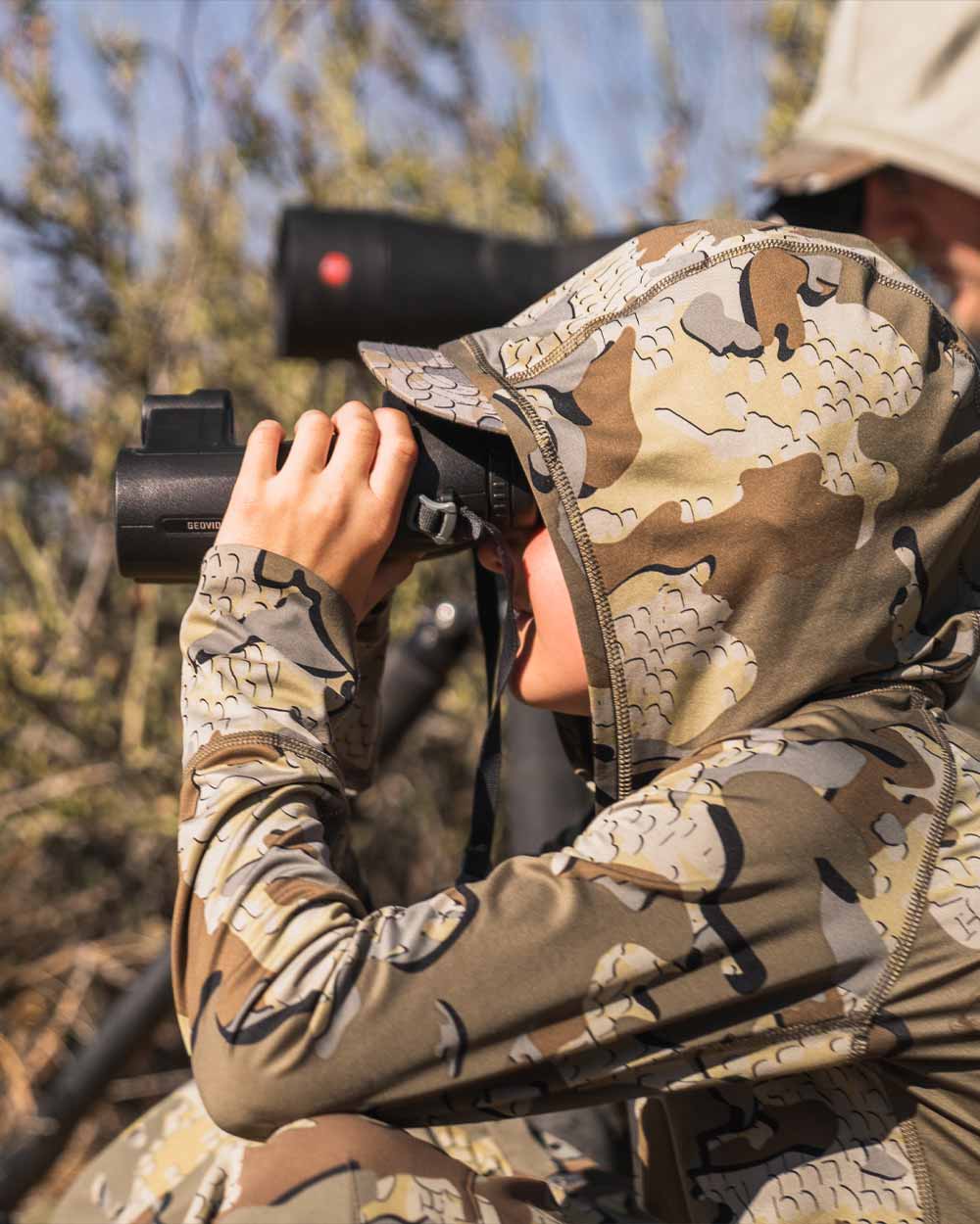 Youth hunter wearing Youth Gila LS Hoodie in Valo Camouflage glassing