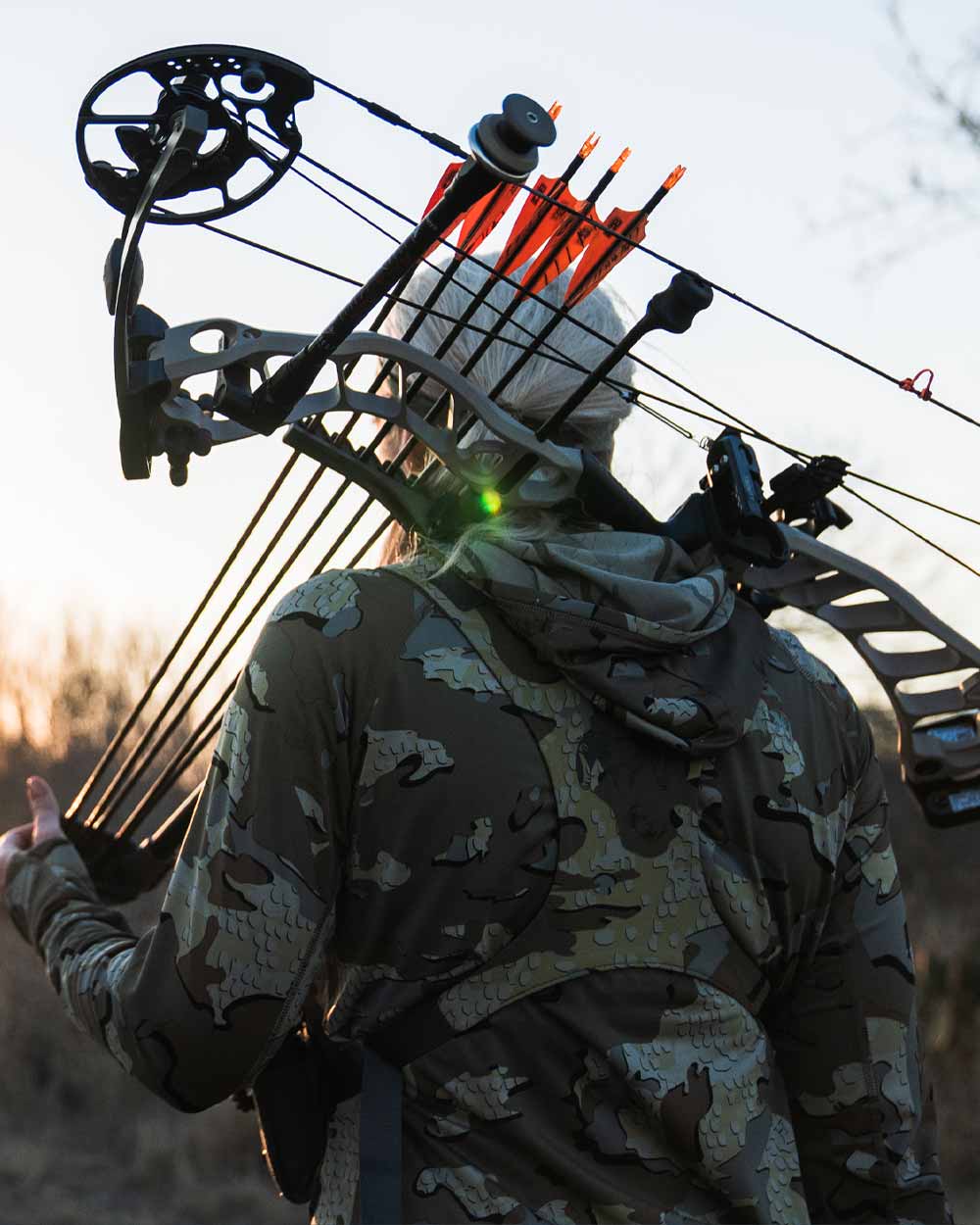 Back of female hunter with outfitted with compound bow and bino harness wearing Women's Gila LS Hoodie in Valo Camouflage