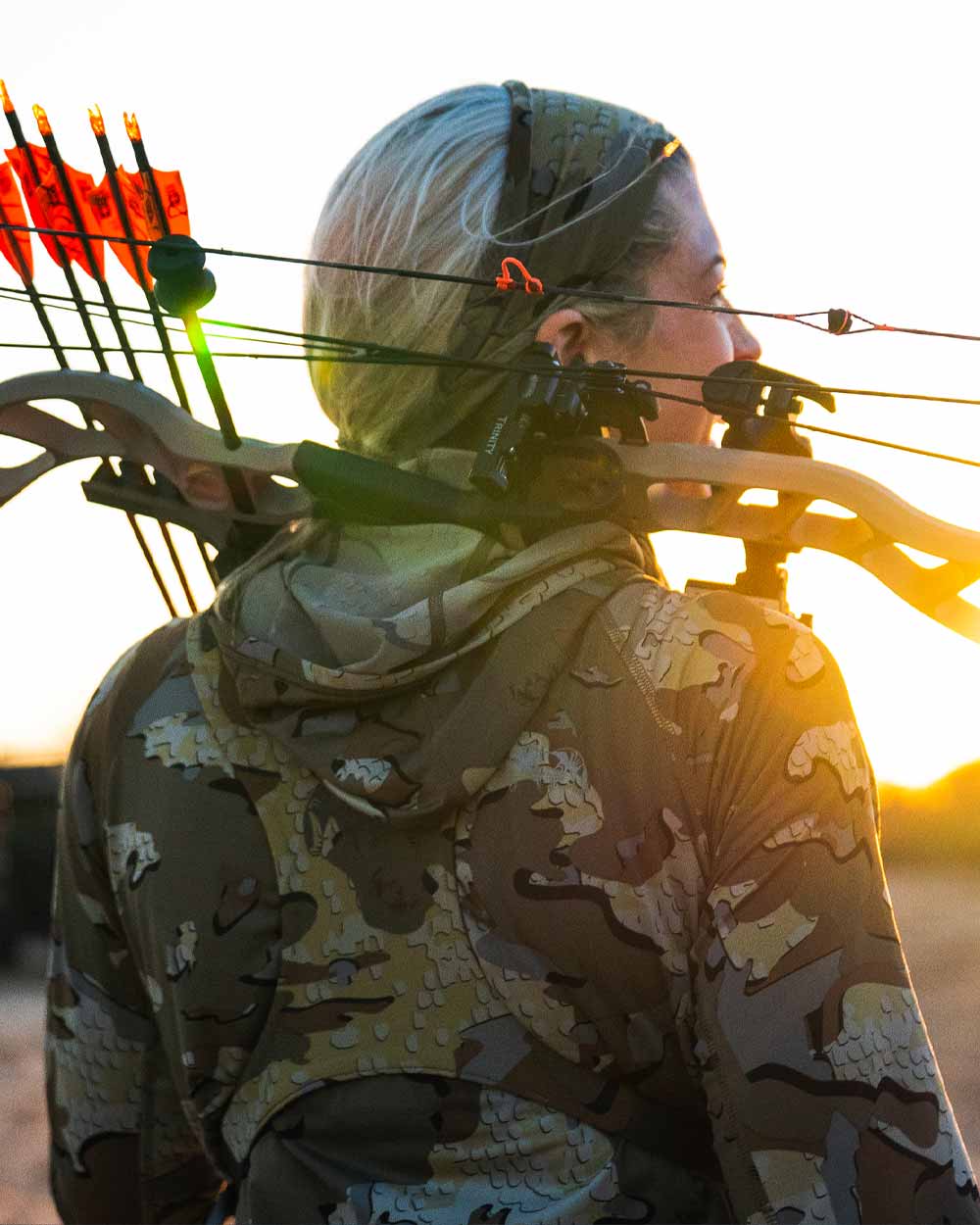 Back of Hunter Holding Bow on Shoulders Wearing Women's Gila Long Sleeve Hoodie in Valo Camouflage