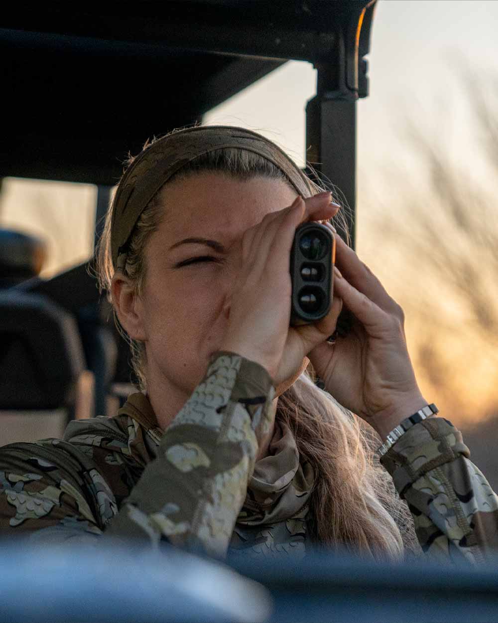 Female hunter using rangefinder wearing Women's Gila LS Hoodie in Valo Camouflage