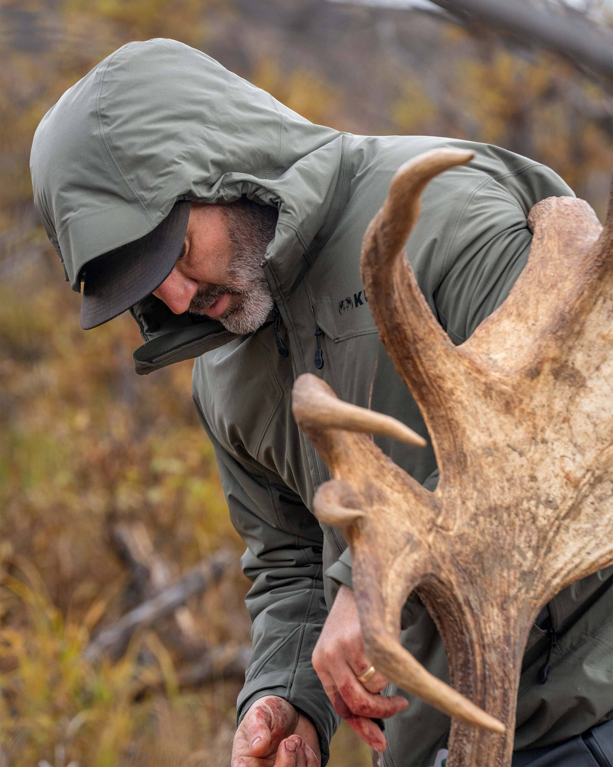 Hunter wearing Mountain PRO Hooded Jacket in Ash Brown cleaning, large palmated moose antlers 