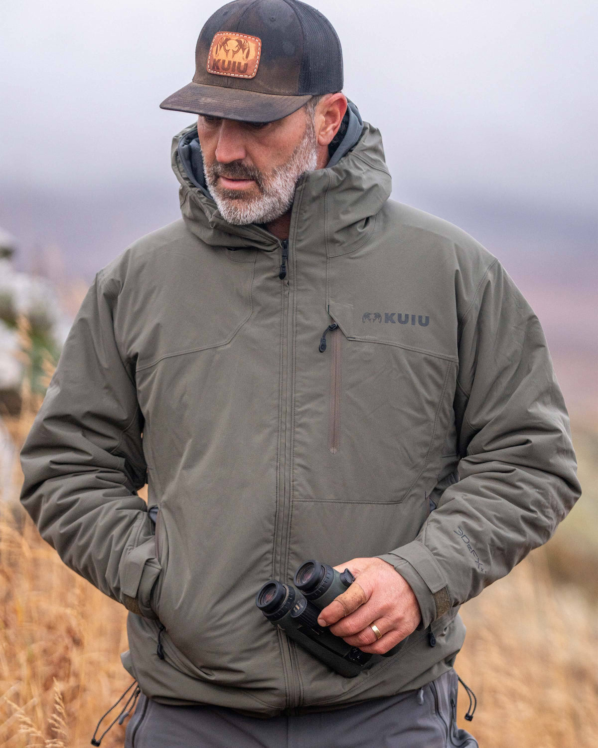 Front of hunter holding a binocular wearing Mountain PRO Hooded Jacket in Ash Brown