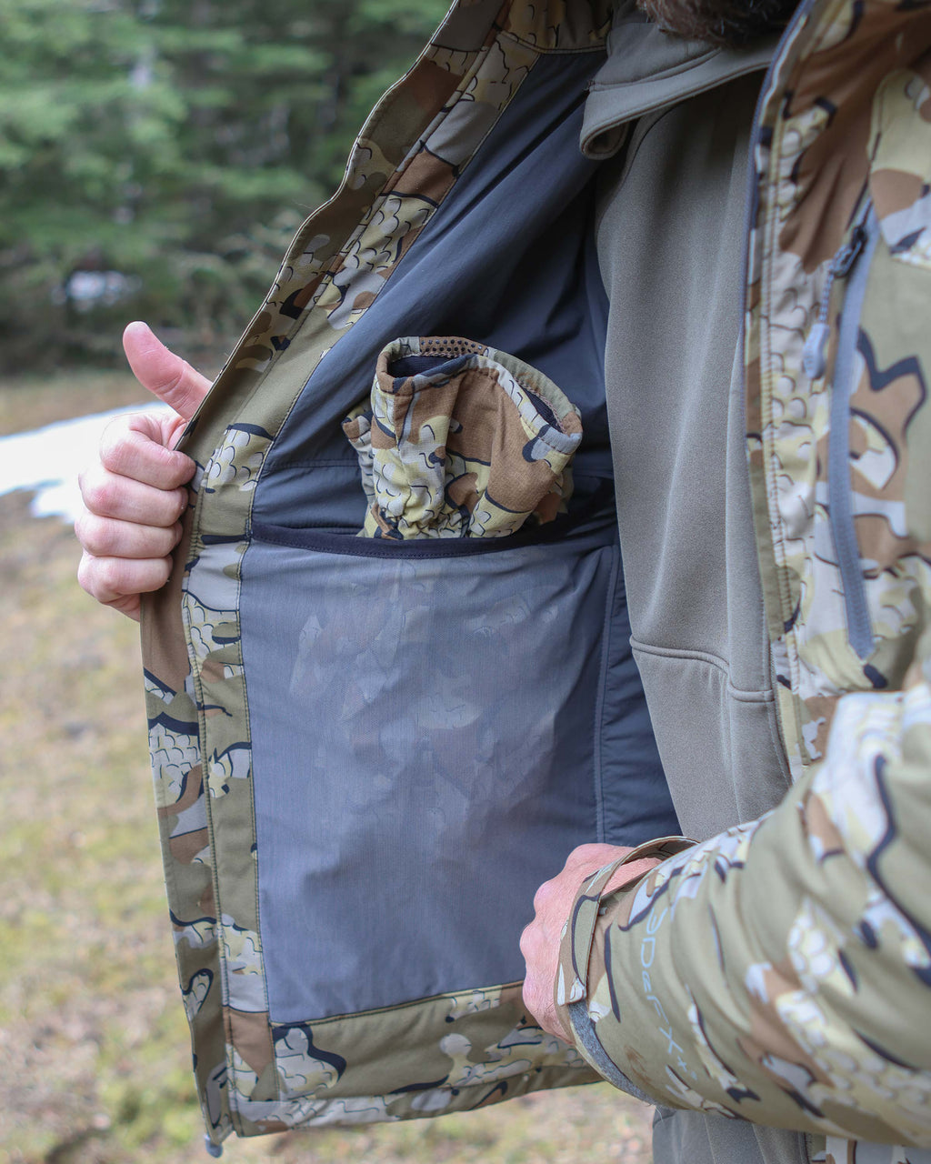 Hunter displaying gloves inside mesh drop pocket on Mountain PRO Hooded Jacket in Valo Camouflage