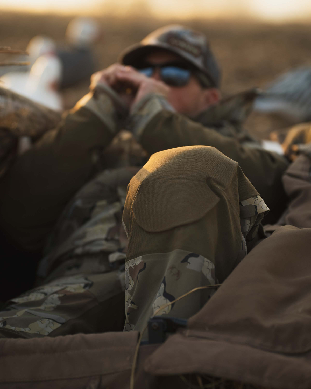 Waterfowl hunter in layout field blind wearing KUIU Paragon Storm Shell Parka and Bib in Valo Camouflage