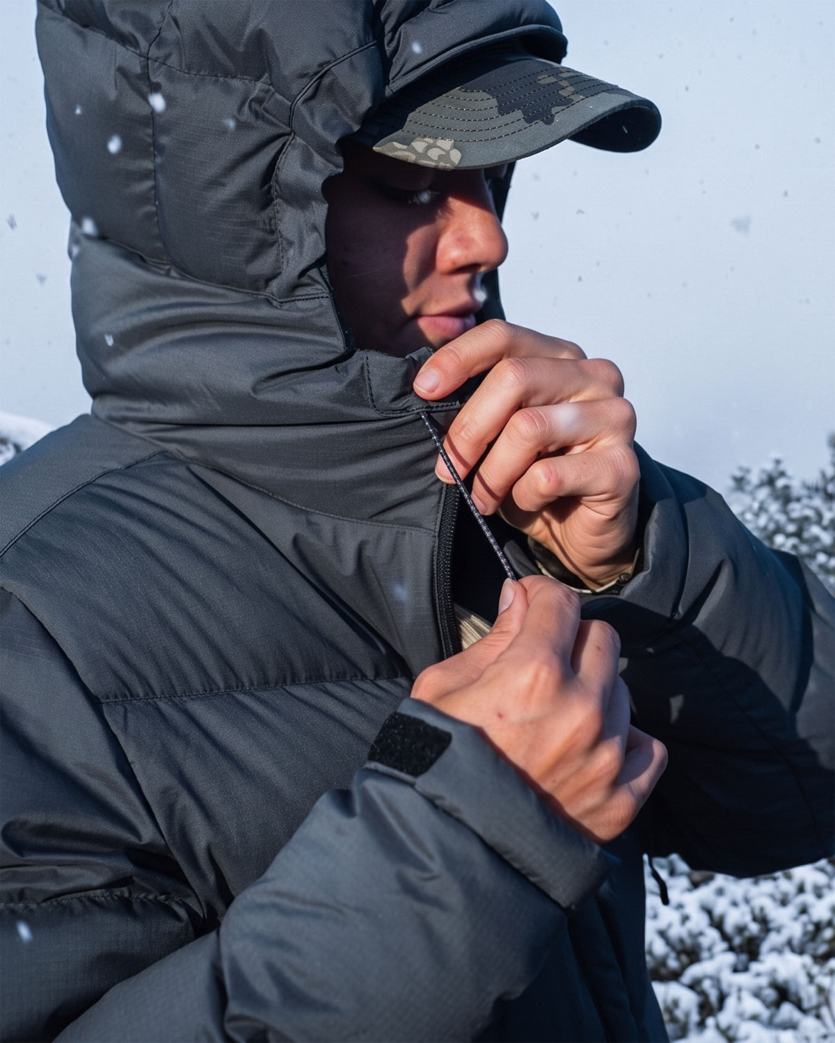 Close-up of woman wearing a Super Down PRO Hooded Jacket in Gunmetal Grey adjusting the hood.