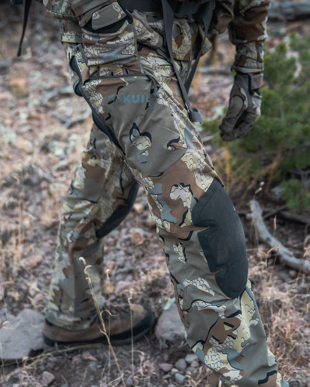 Hunter wearing PRO Pant in Valo camouflage reaching into the unzipped cargo pocket on the thigh