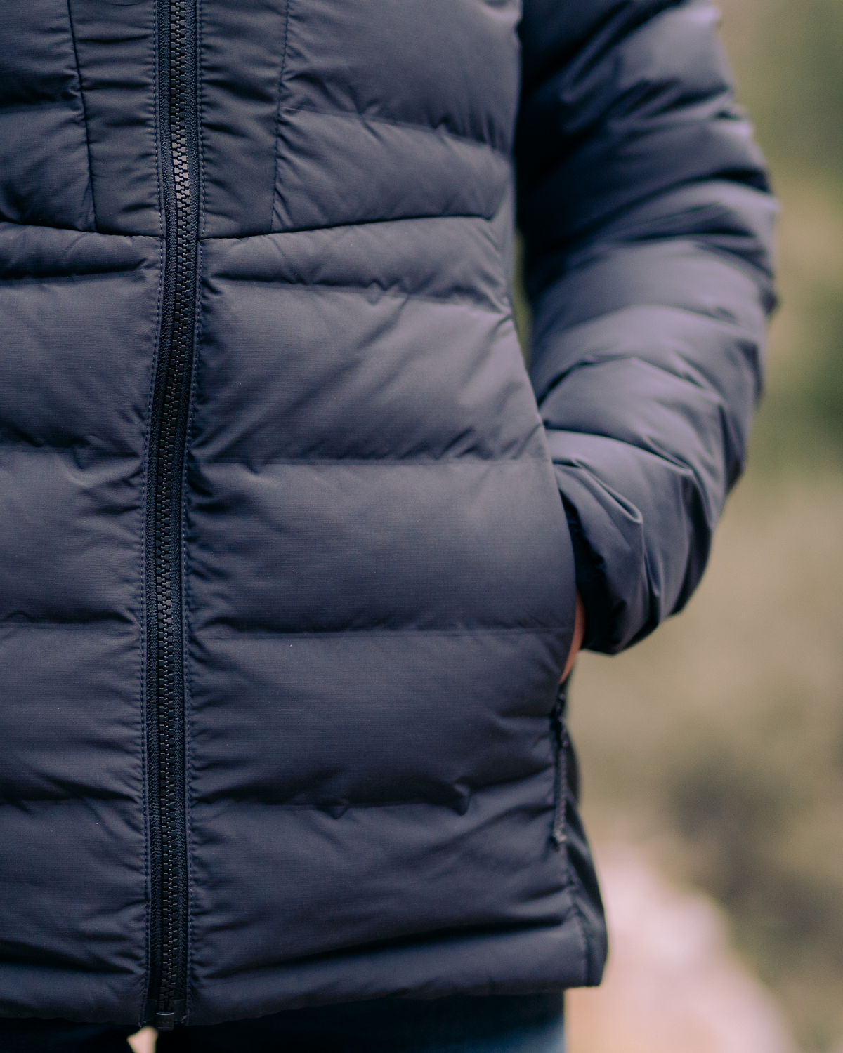 Woman's hand inside zippered hand pockets of the Elements Hooded Jacket in Gunmetal